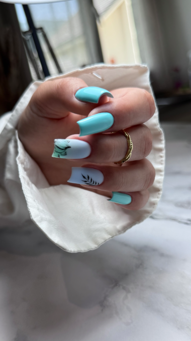 Main envenagée avec des ongles longs turquoise et blancs, décorés de motifs.