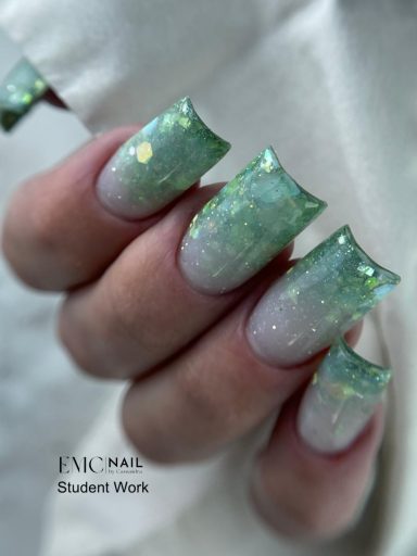 Ongles longs avec vernis vert irisé et paillettes scintillantes.