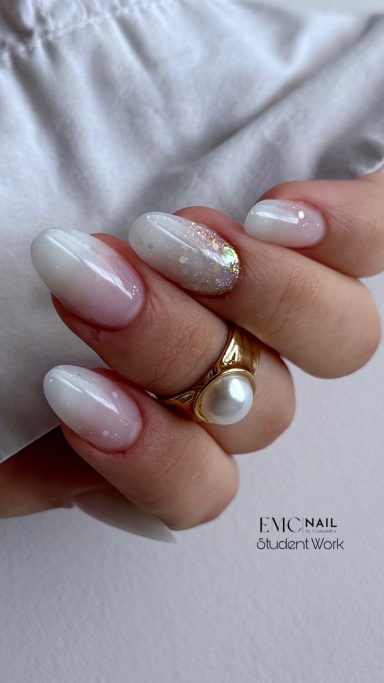 Ongles vernis en dégradé blanc avec un anneau doré et une perle.
