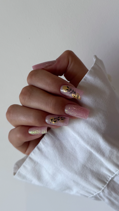 Main droite avec des ongles en dégradé et motifs, tenant une manche blanche.